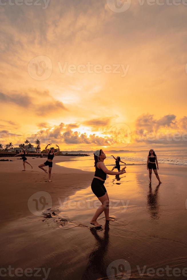 uma grupo do ásia mulheres dançando juntos e cheio do alegria em a de praia foto