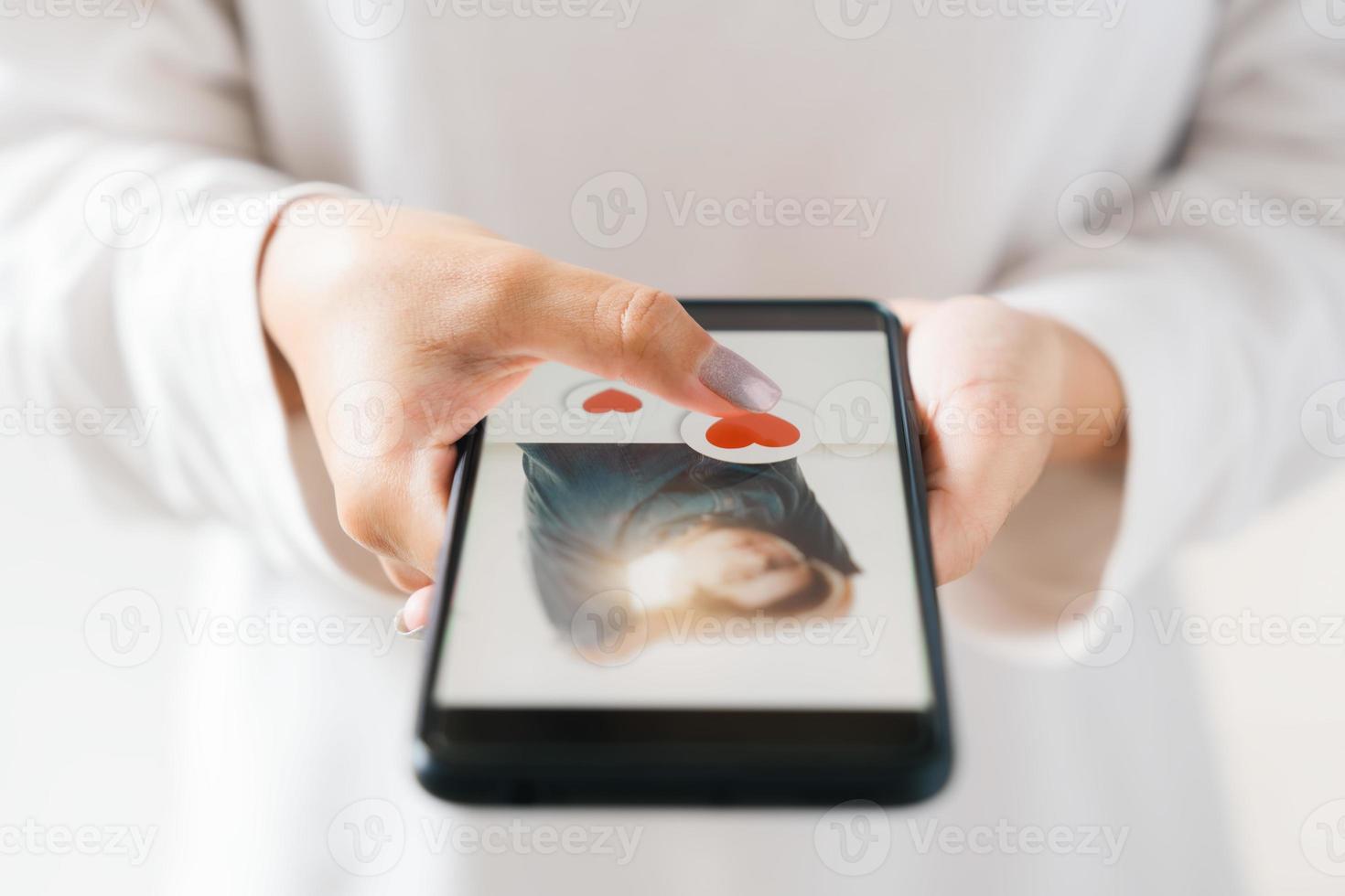 dia dos namorados dia e amor dia conceito, mulher dedo tocante coração ícone em tela dentro Smartphone aplicativo, feliz mulher postagem amor coração emoji ícone botão, procurar aplicativo conectados casal. foto