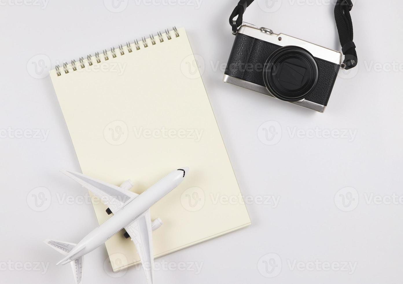 plano deitar do em branco página aberto caderno, avião modelo e Câmera em branco fundo com cópia de espaço. viagem, foto e memória conceito.