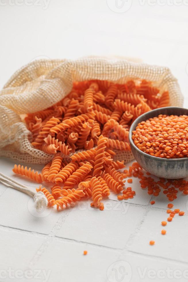 macarrão de lentilha vermelha fusilli em um fundo de azulejo branco. foto