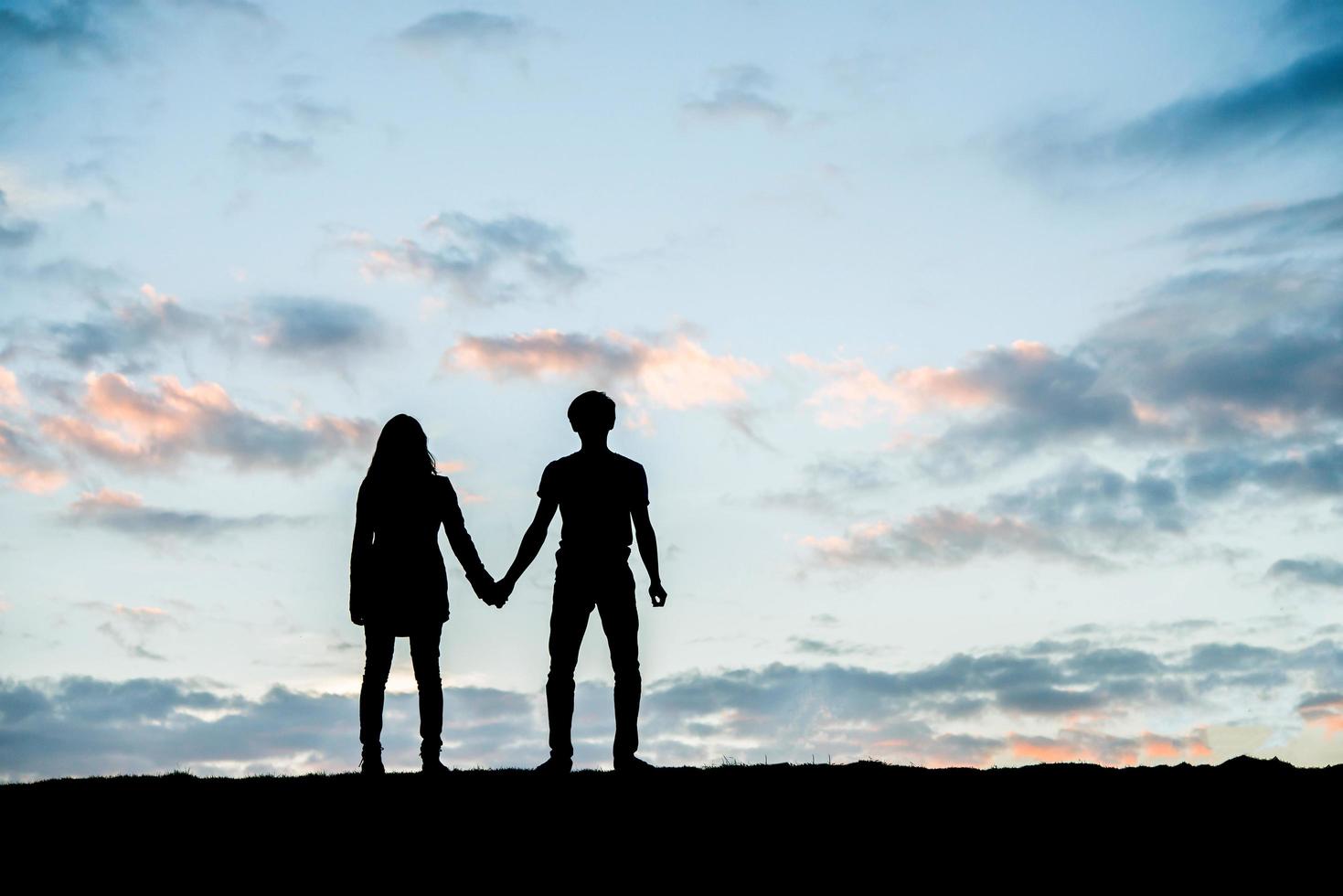 silhueta de um jovem casal feliz juntos contra o lindo pôr do sol foto