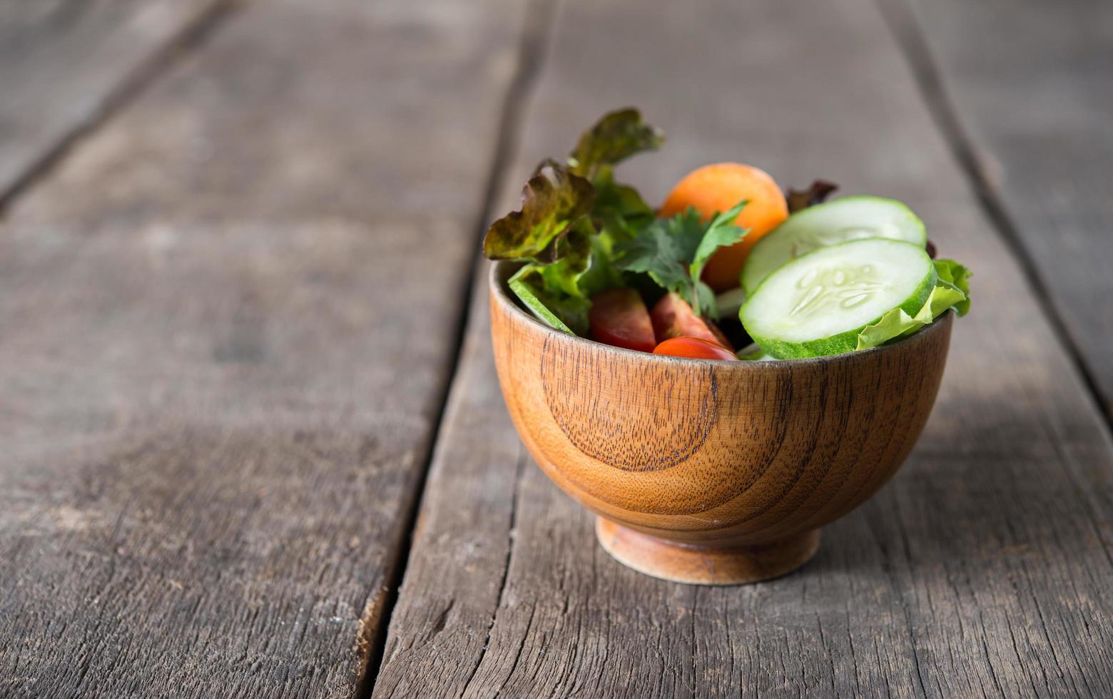 salada de legumes fresca em fundo de madeira foto