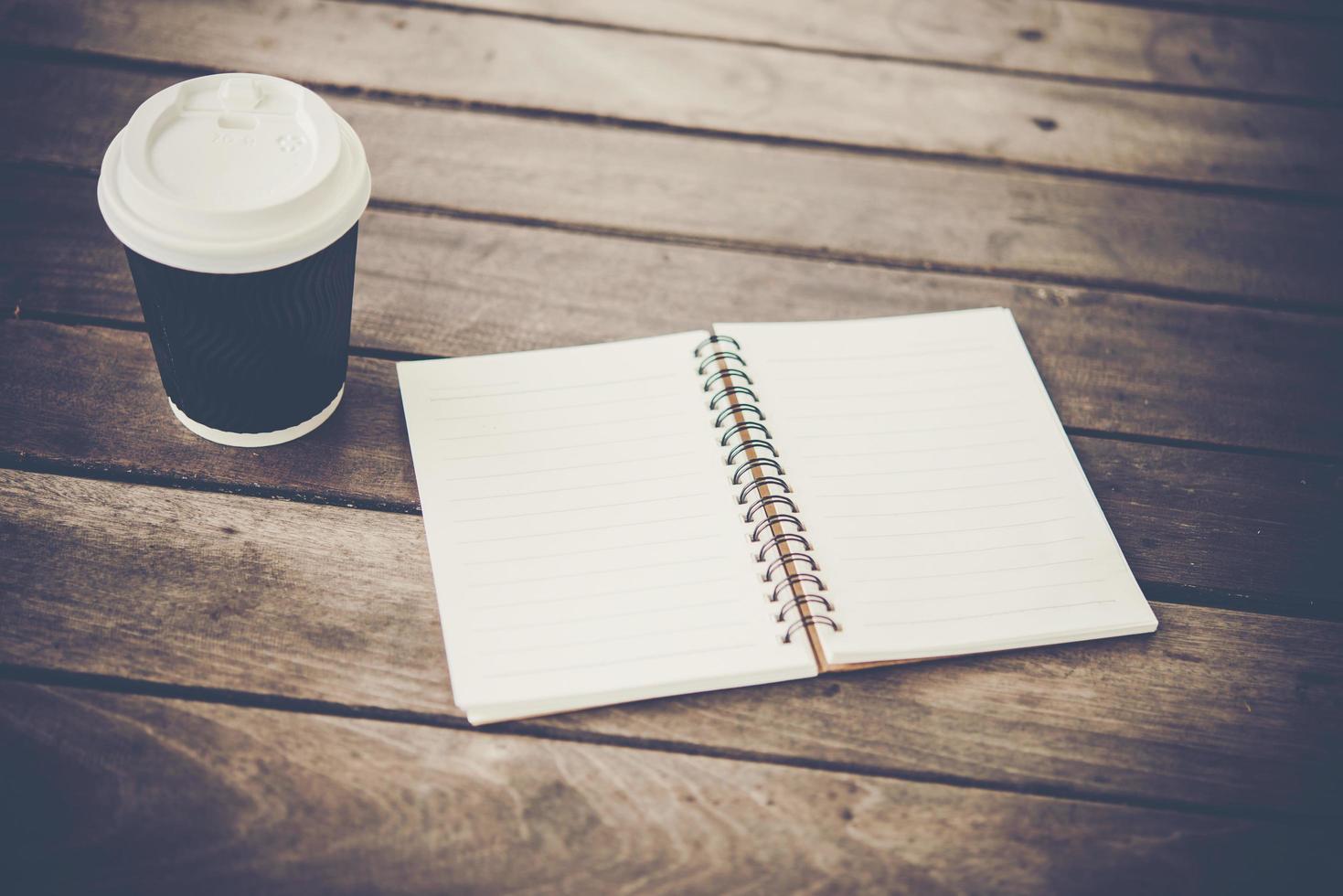 caderno em branco e xícara de café em uma mesa de madeira foto