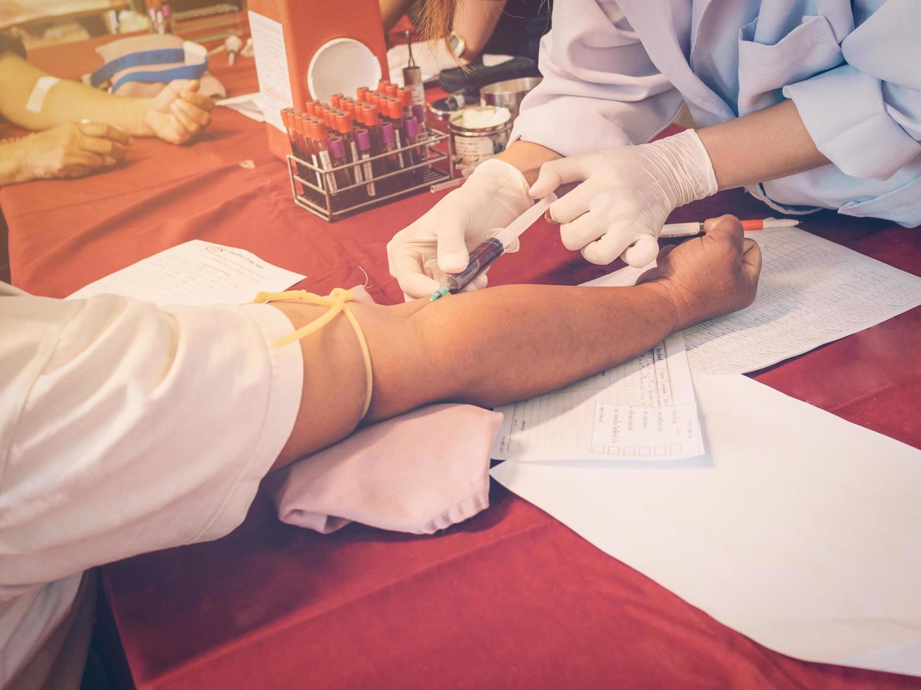 fechar acima mão homem e enfermeira levando uma sangue amostra com vintage filtro. foto