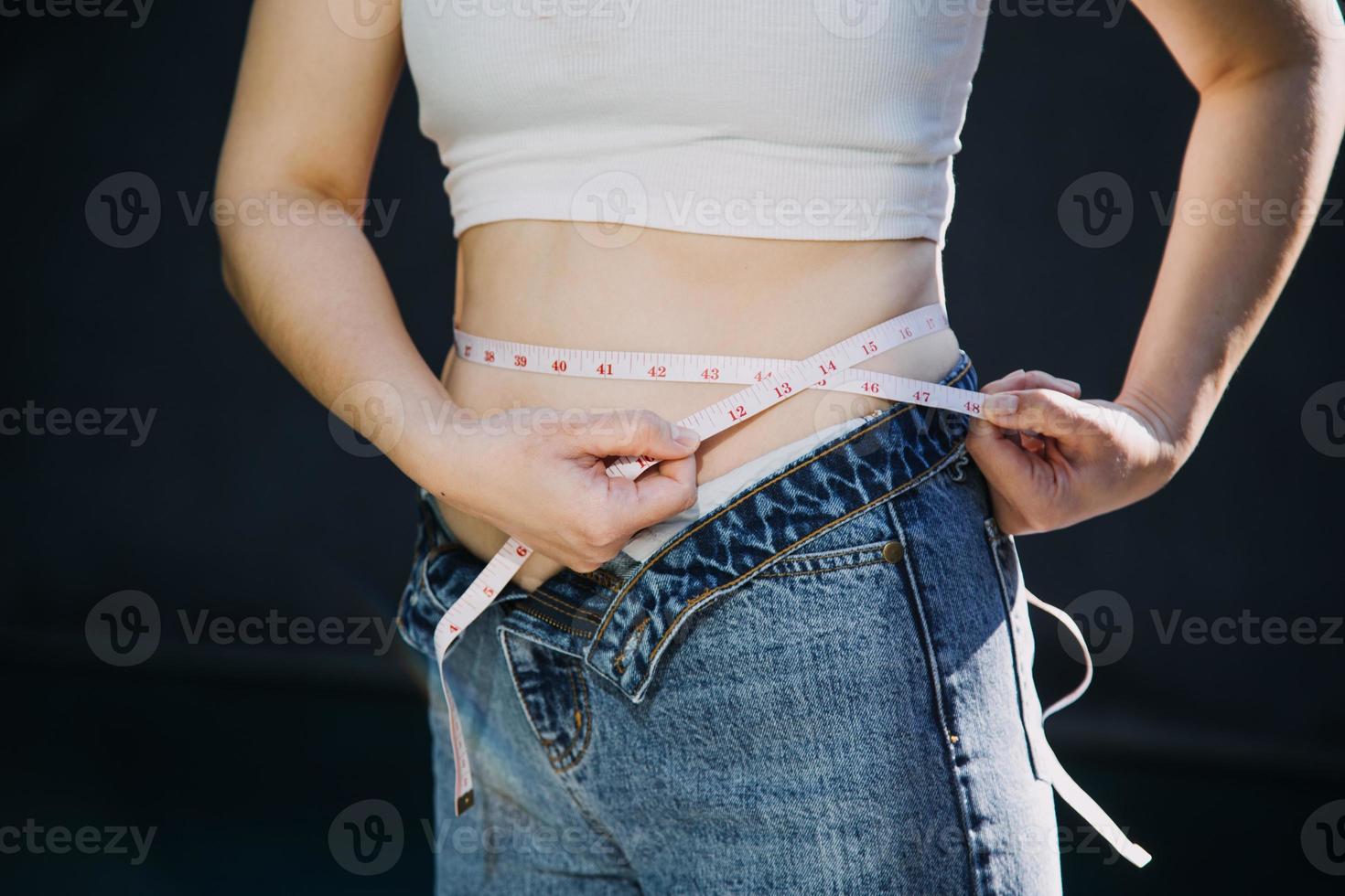 mulher gorda, barriga gorda, gordinha, mão de mulher obesa segurando gordura excessiva da barriga com fita métrica, conceito de estilo de vida de dieta de mulher foto