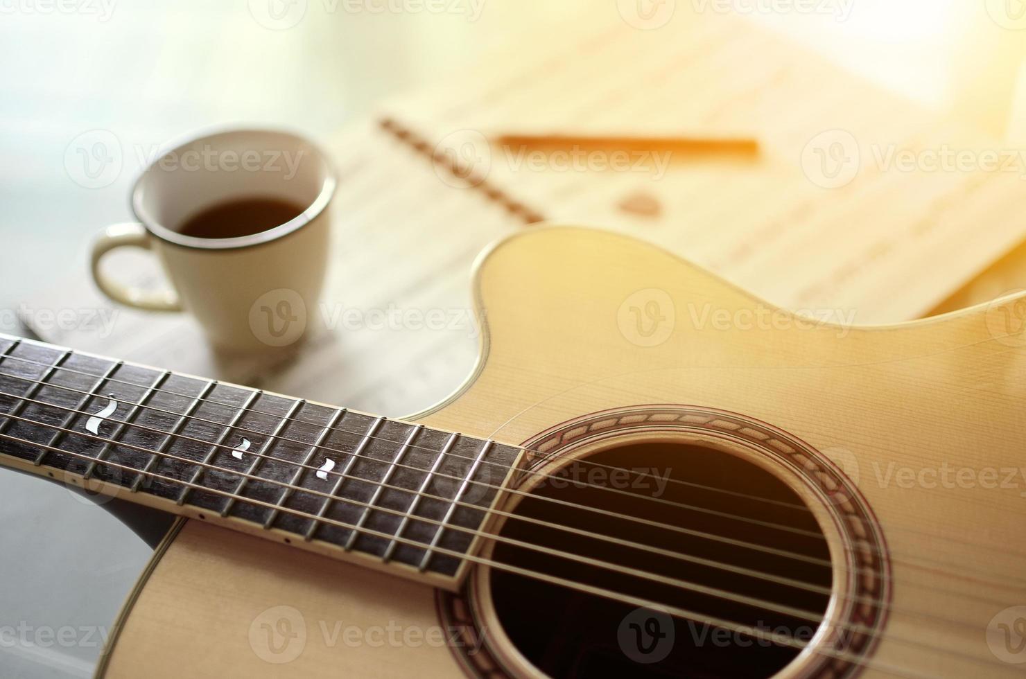 acústico guitarra e uma copo do café em fundo foto