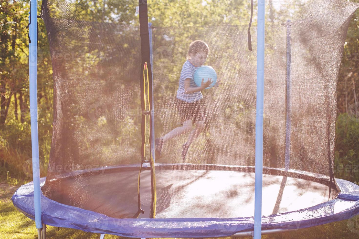 Garoto pulando em trampolim. criança jogando com uma bola em uma trampolim foto
