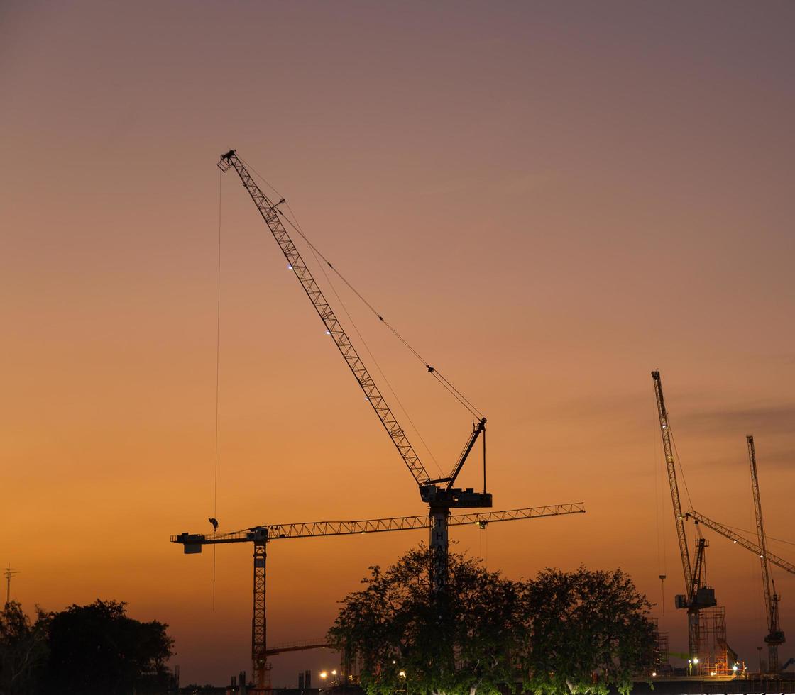 guindastes de construção em bangkok ao pôr do sol foto