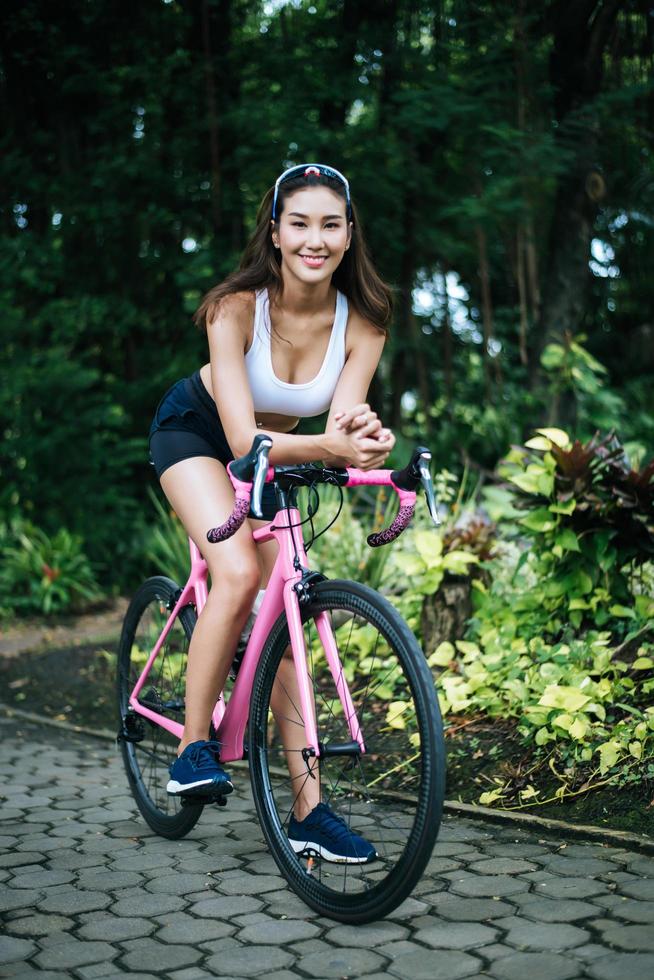 retrato de uma mulher com uma bicicleta rosa no parque foto