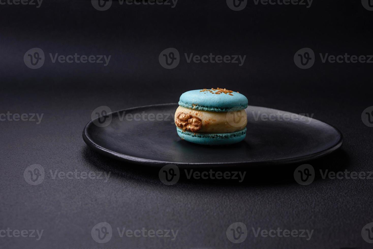 lindo saboroso macaron com o preenchimento e fruta sabor em uma Preto prato foto