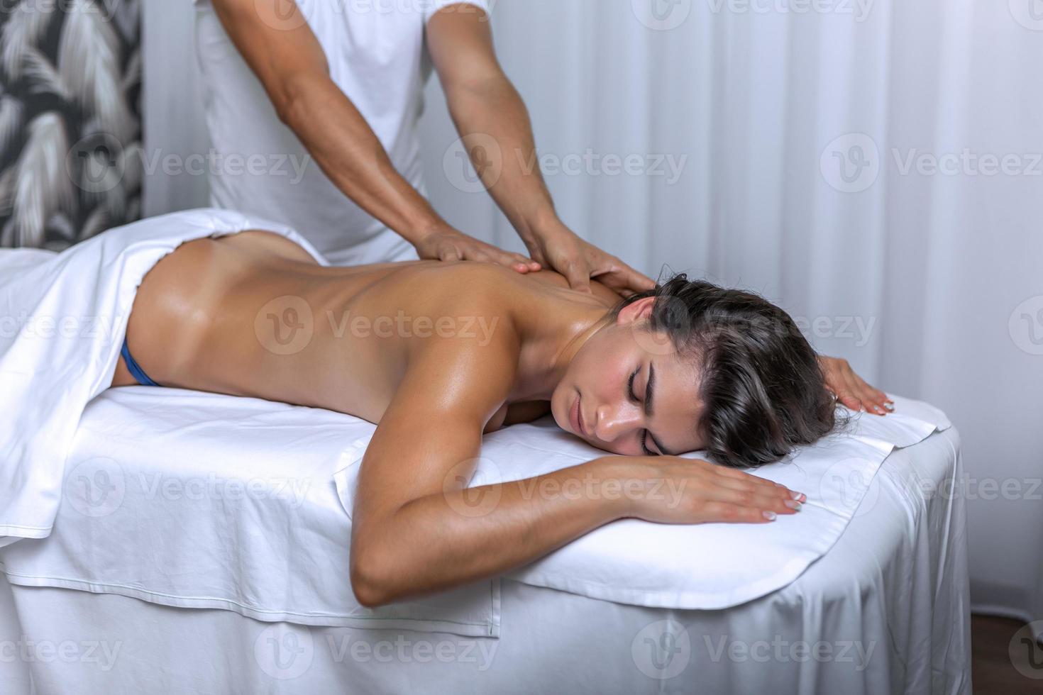 mulher recebendo costas massagem às spa Centro de irreconhecível masculino massagista foto