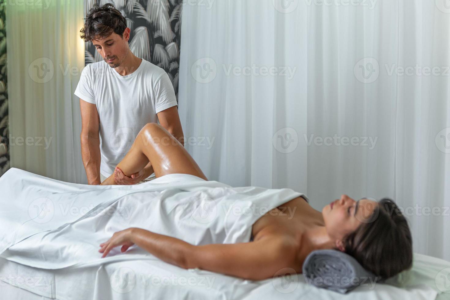 mulher recebendo uma perna massagem a partir de uma masculino terapeuta dentro uma spa salão foto