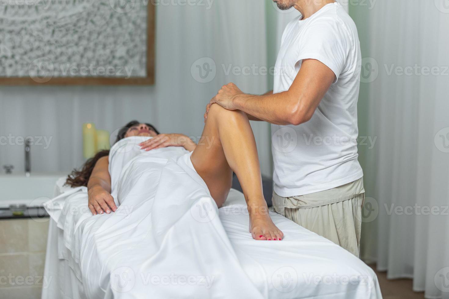 terapeuta fazendo uma perna massagem para mulher dentro spa salão foto