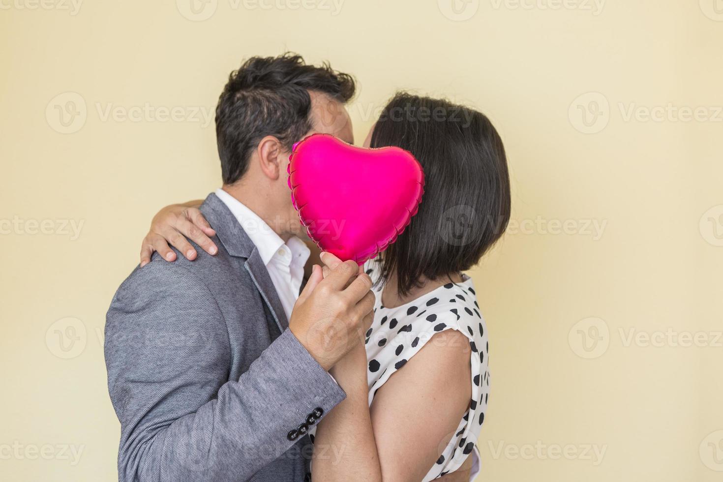 amoroso casal se beijando e se escondendo atrás balão foto