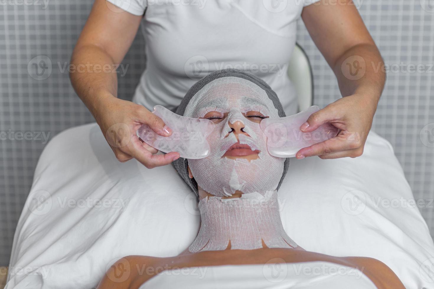 fechar acima do mulher dentro spa recebendo gua sha facial massagem tratamento de esteticista foto