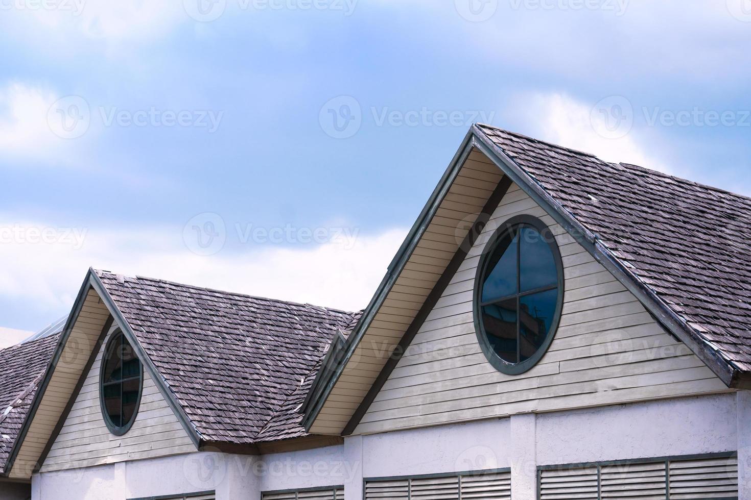 lindo de madeira casa cobertura com uma volta janela em azul céu fundo foto