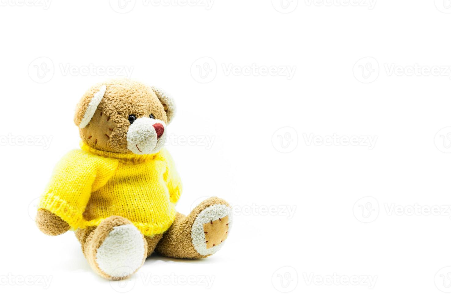 Castanho Urso de pelúcia Urso brinquedo vestem amarelo camisas sentado em branco fundo foto