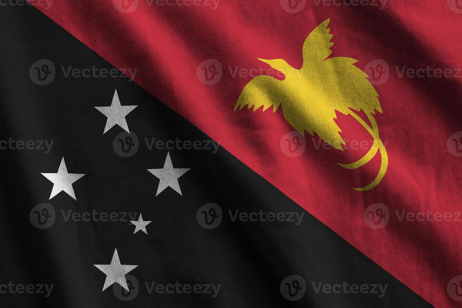 bandeira de papua nova guiné com grandes dobras acenando perto sob a luz do estúdio dentro de casa. os símbolos e cores oficiais no banner foto