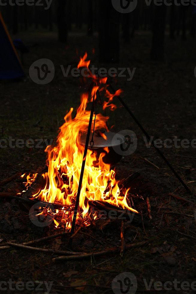 cozinhar ao ar livre em condições de campo. caldeirão em um incêndio na floresta. cozinhando na fogueira durante a viagem. tripé com um chapéu-coco em um incêndio no piquenique. viagens conceituais, trekking e aventura foto