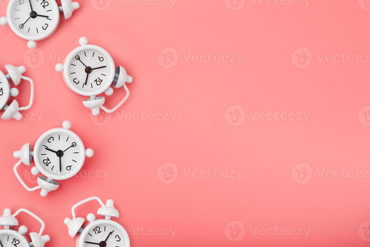 uma padronizar do muitos branco clássico alarme relógios dentro a Formato do uma padronizar em uma Rosa fundo. topo Visão com uma cópia de do a espaço, plano deitar. foto