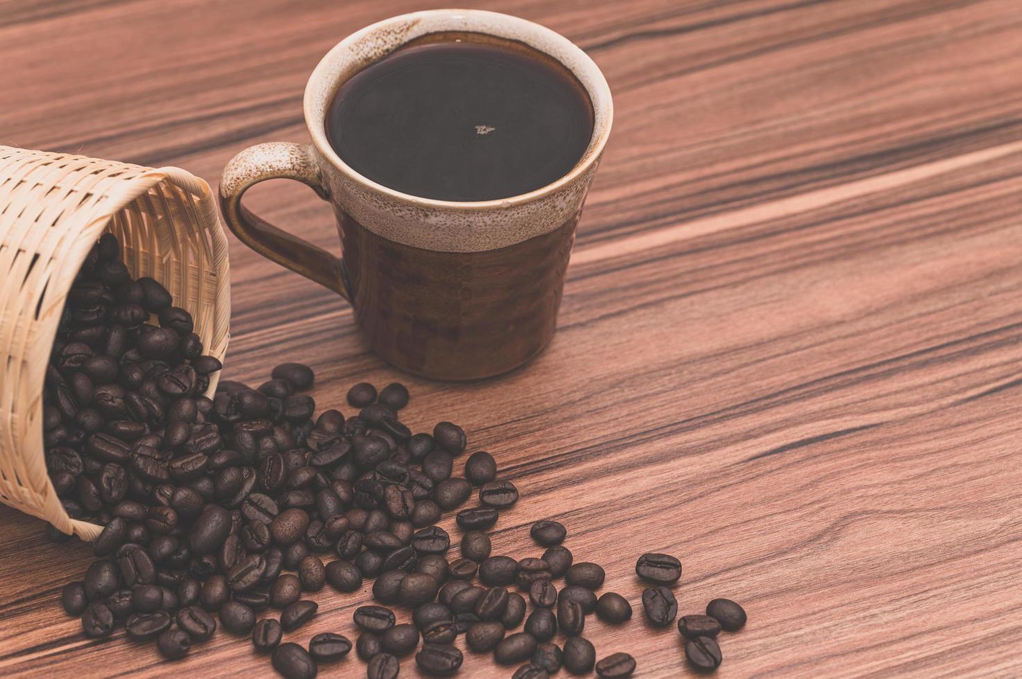 grãos de café e xícara de café na mesa foto