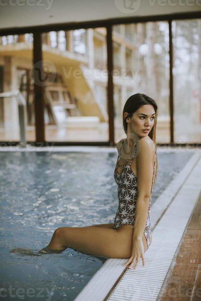 bela jovem sentada à beira da piscina foto
