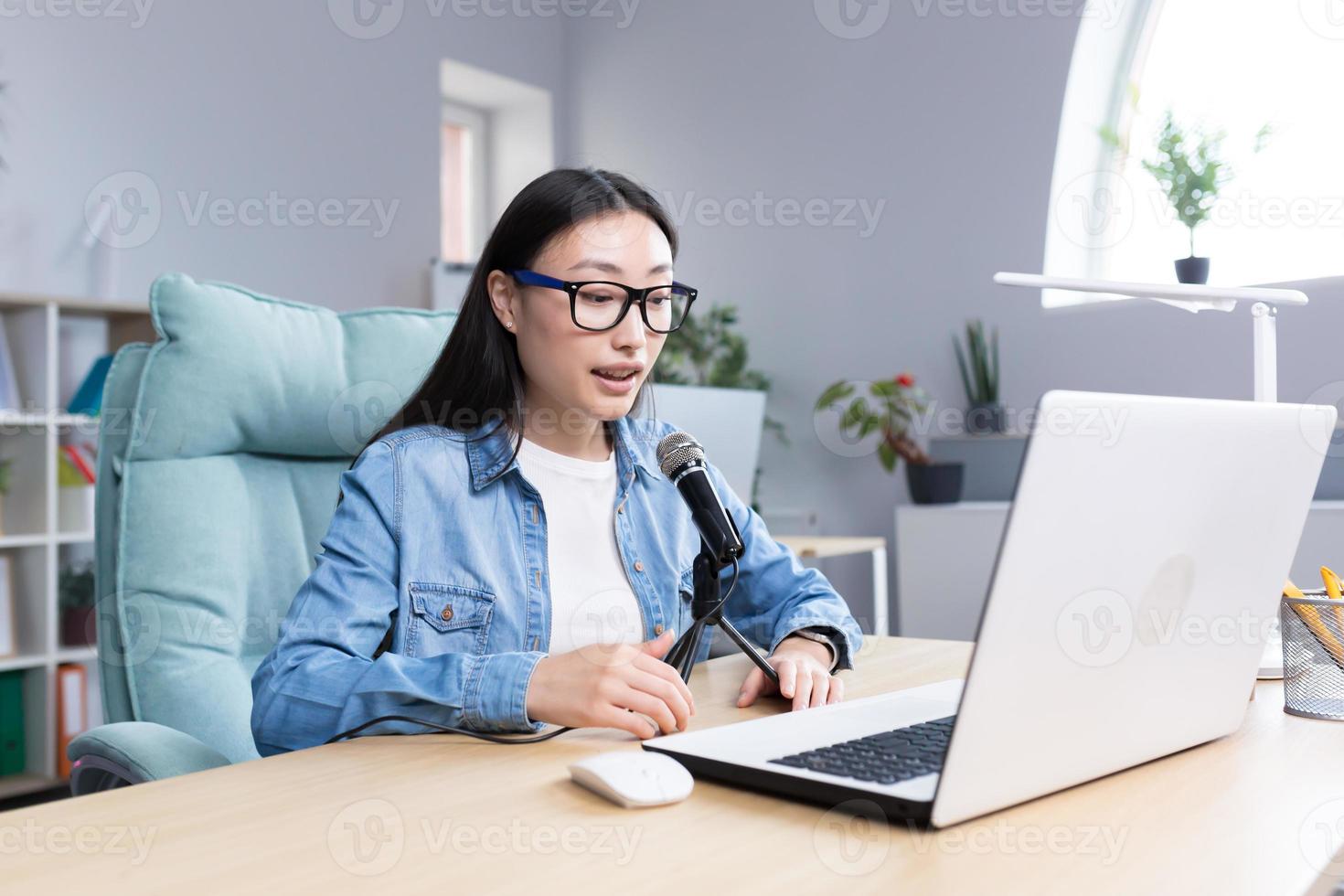 jovem lindo ásia mulher gravação audio podcast, mulher dentro escritório usando profissional microfone foto