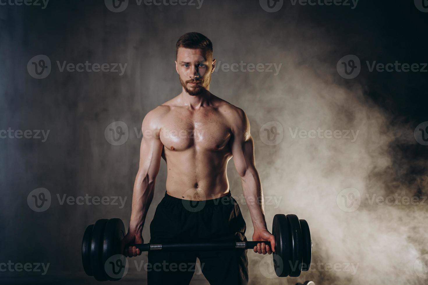 masculino loiro atleta elevadores halteres com mão em bíceps estúdio foto com pingos de chuva