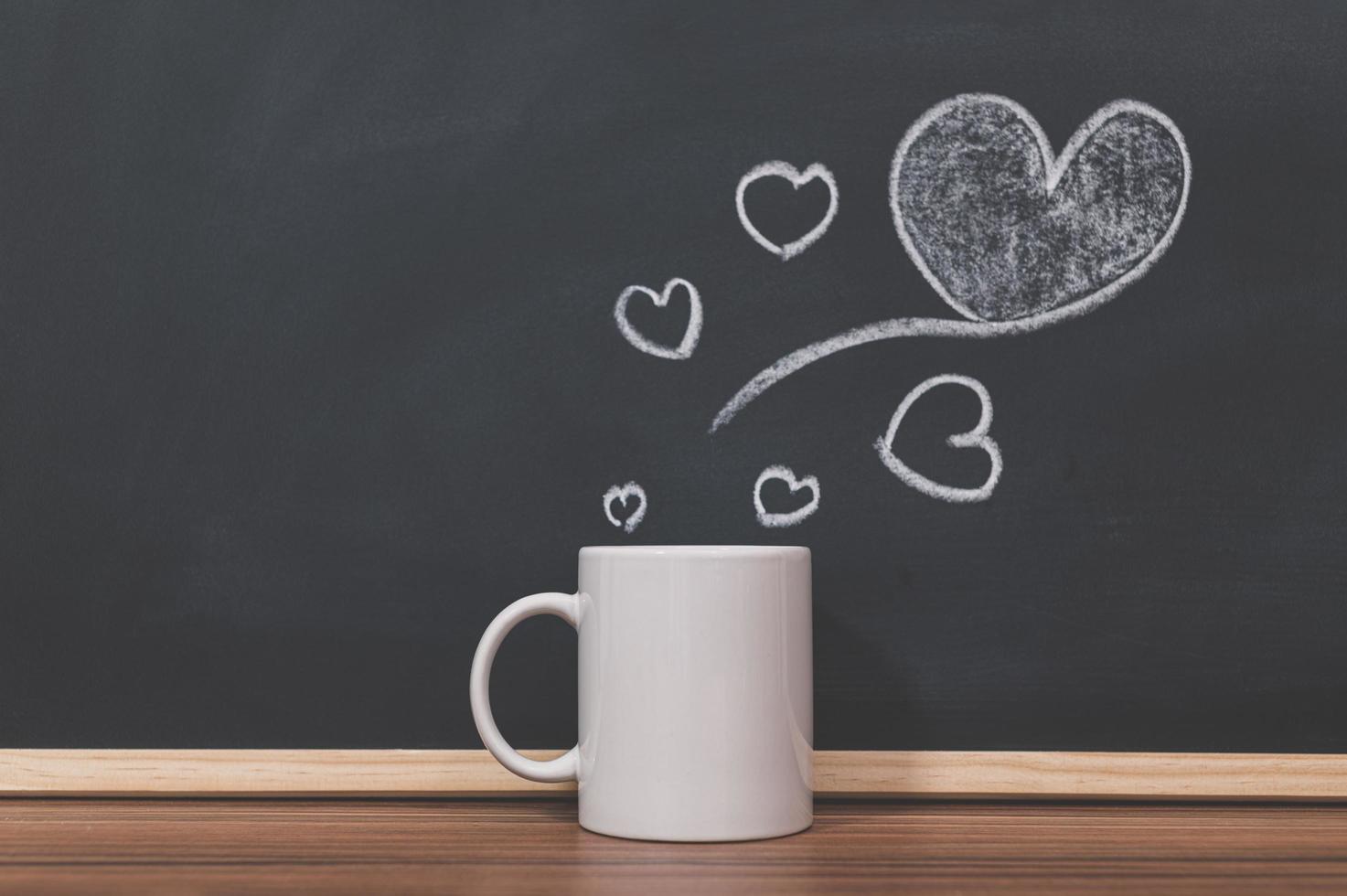 caneca de café e desenho de coração na lousa foto