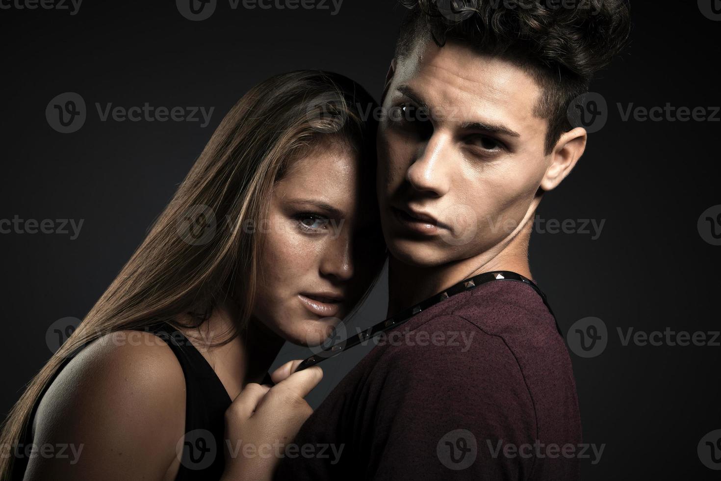 retrato de um lindo casal jovem e feliz contra um fundo cinza escuro foto