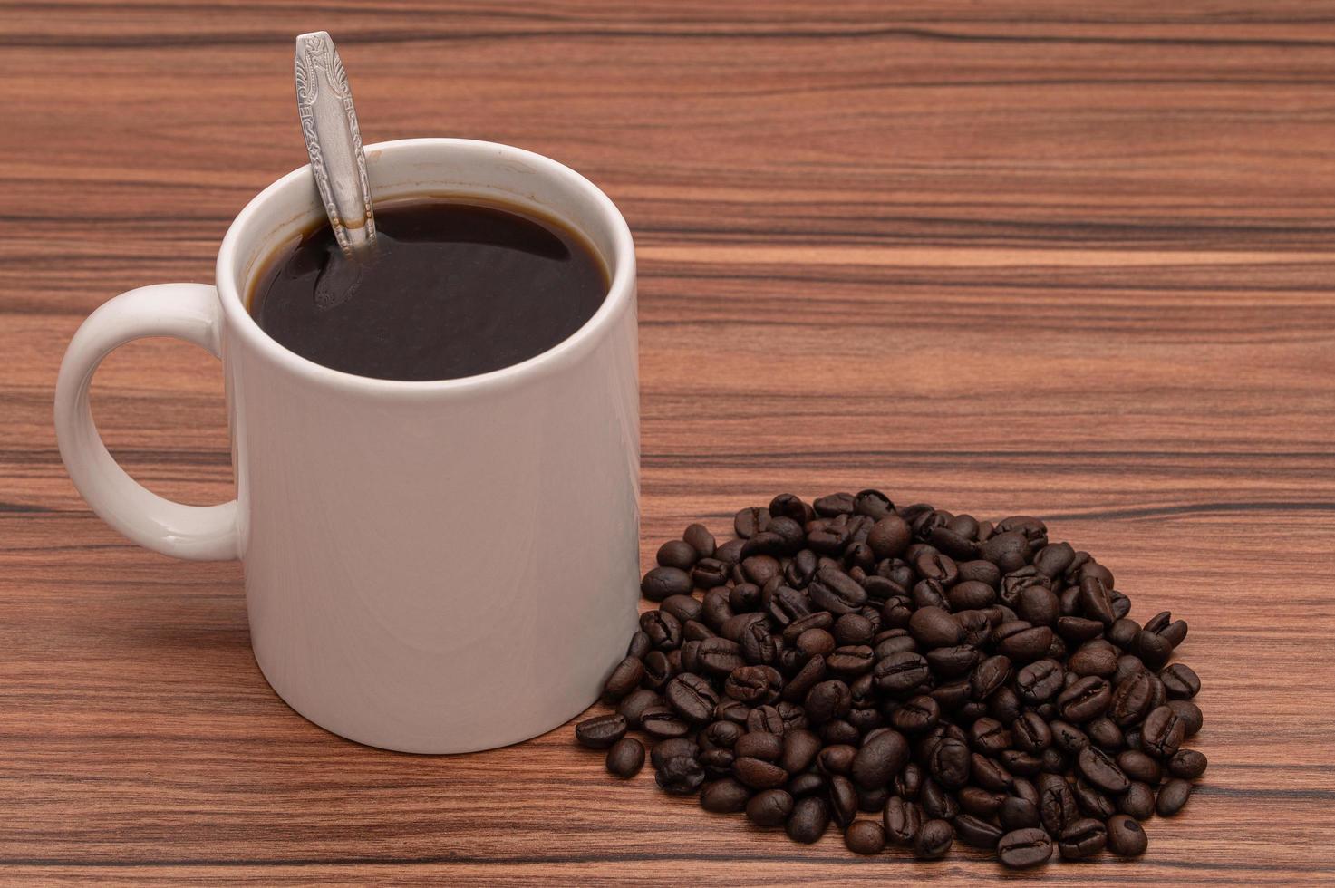 caneca de café e grãos de café na mesa foto