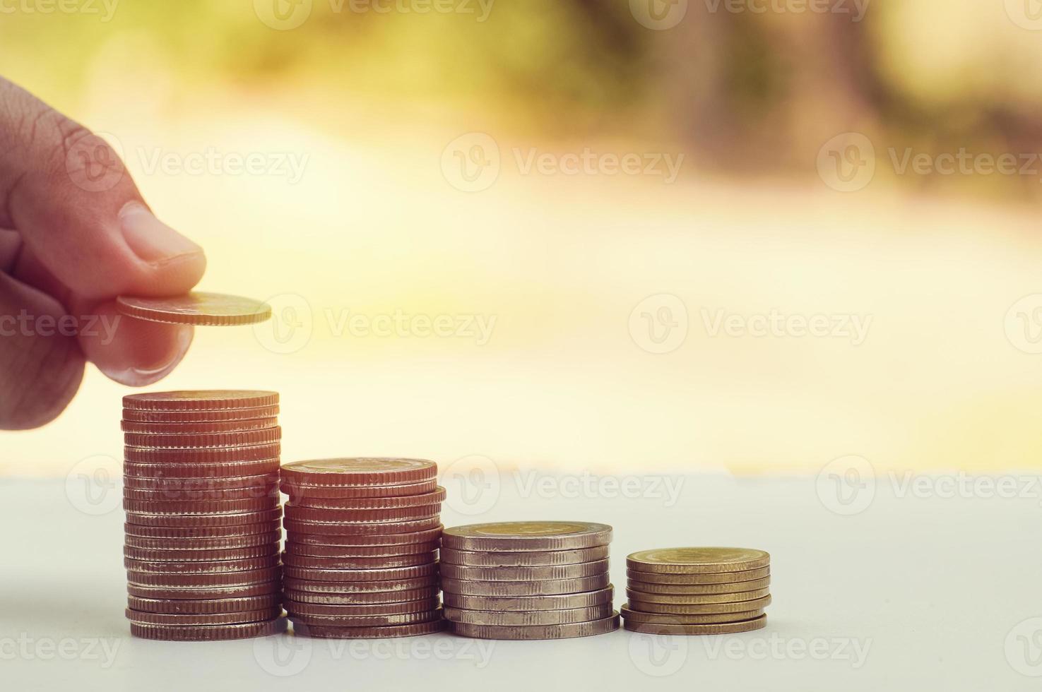 mão colocando dinheiro na pilha de moedas foto