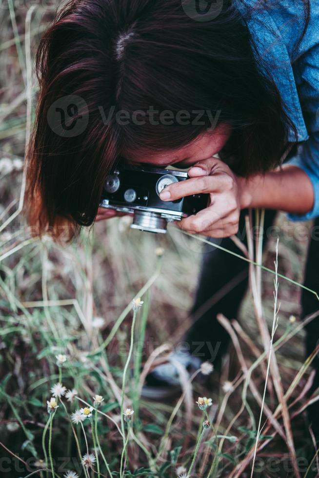 mulher feliz jovem hippie com câmera vintage em campo foto