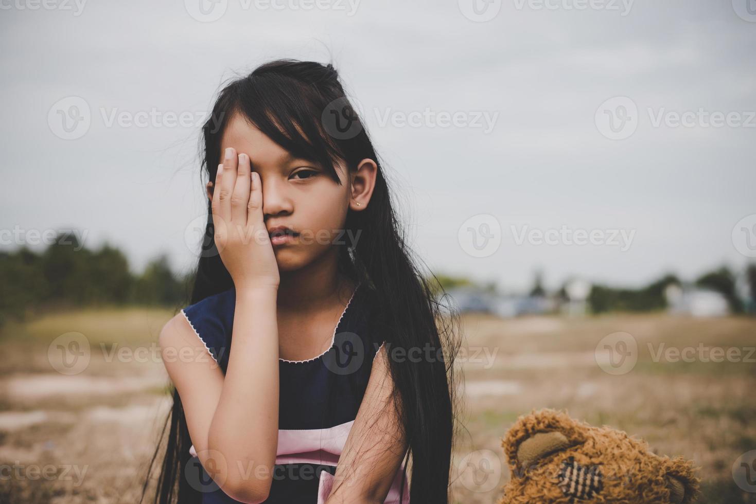 menina sentada com seu urso chateada foto