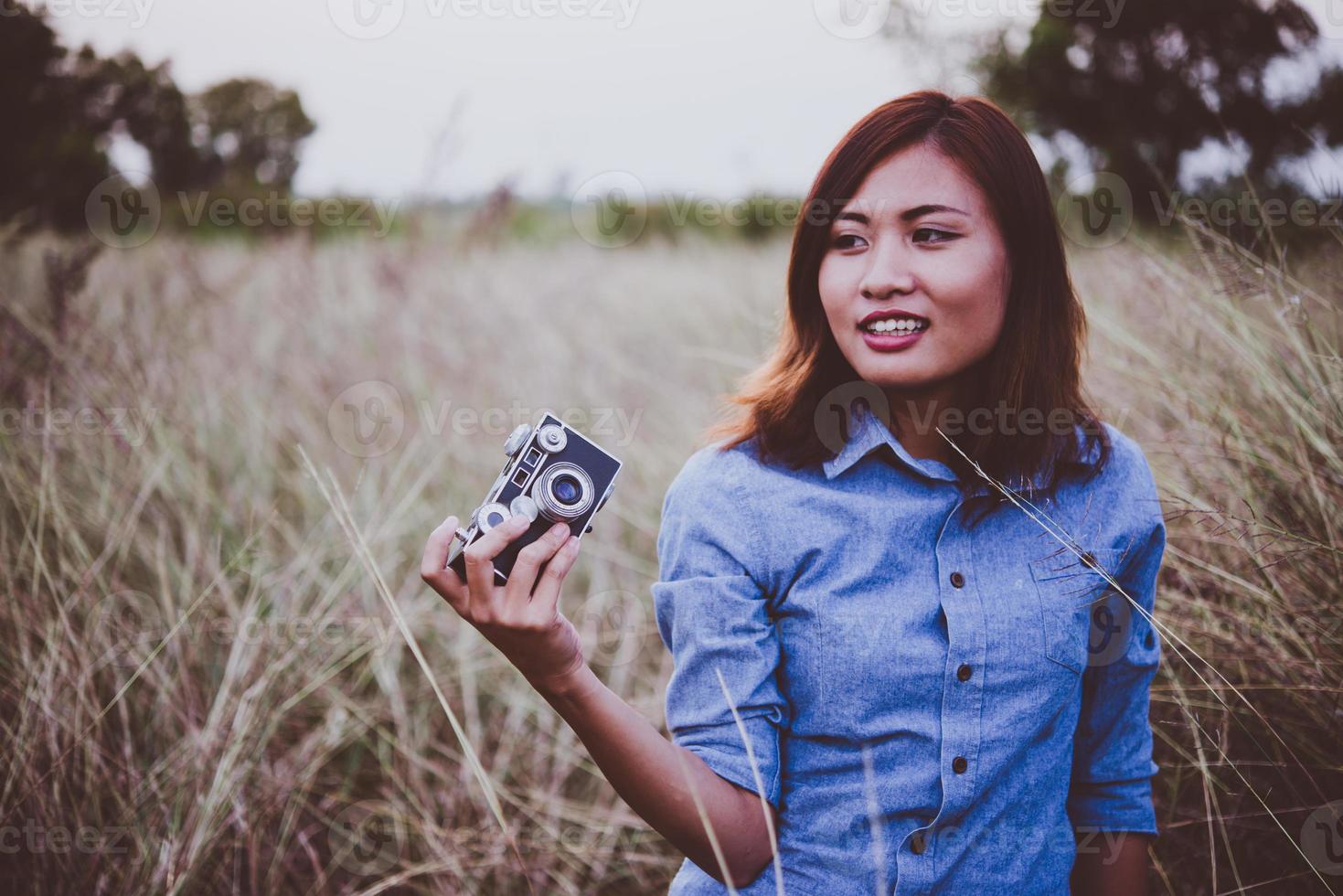 mulher feliz jovem hippie com câmera vintage em campo foto