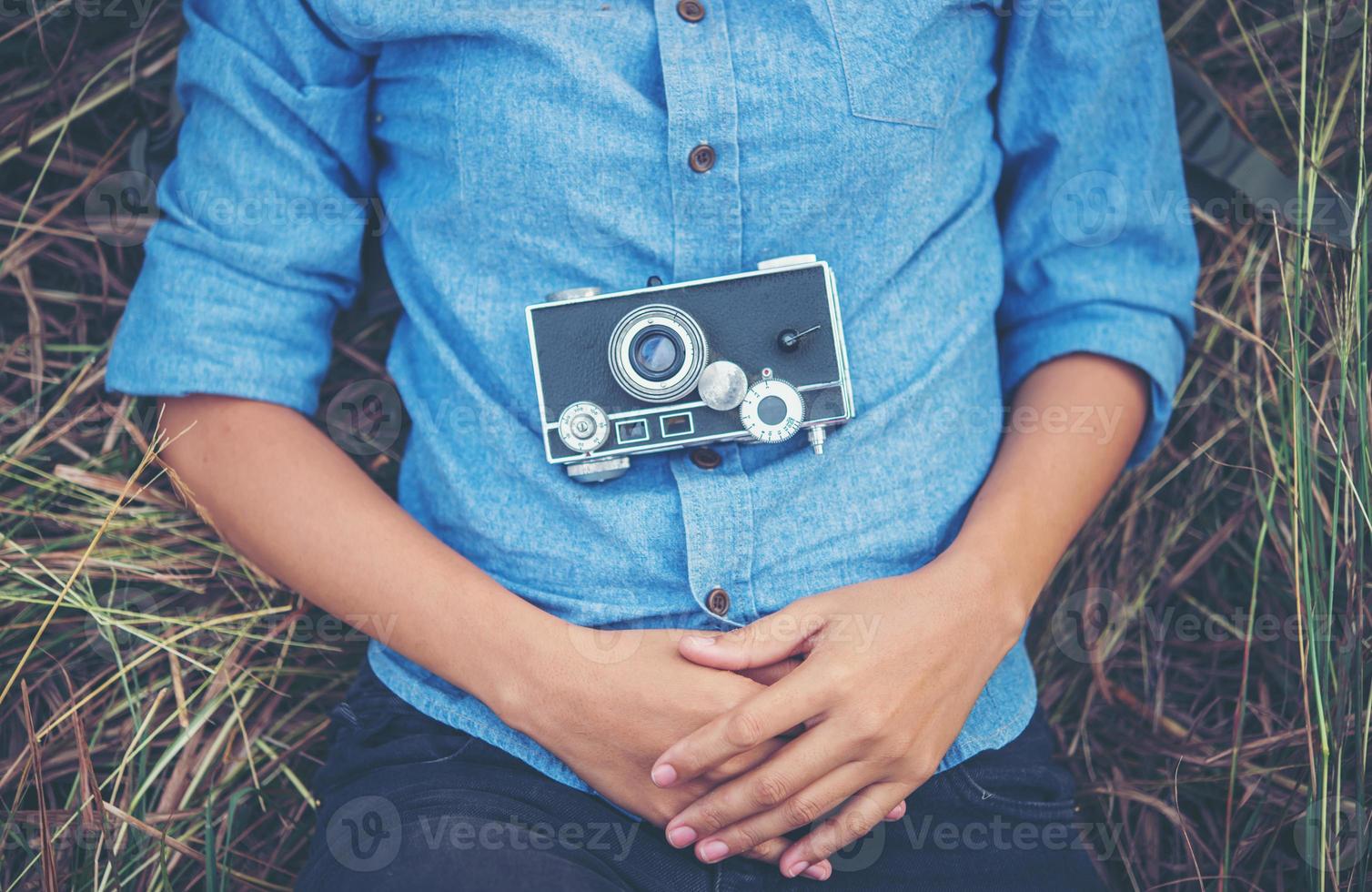 mulher jovem hippie com uma câmera vintage deitada em um campo foto