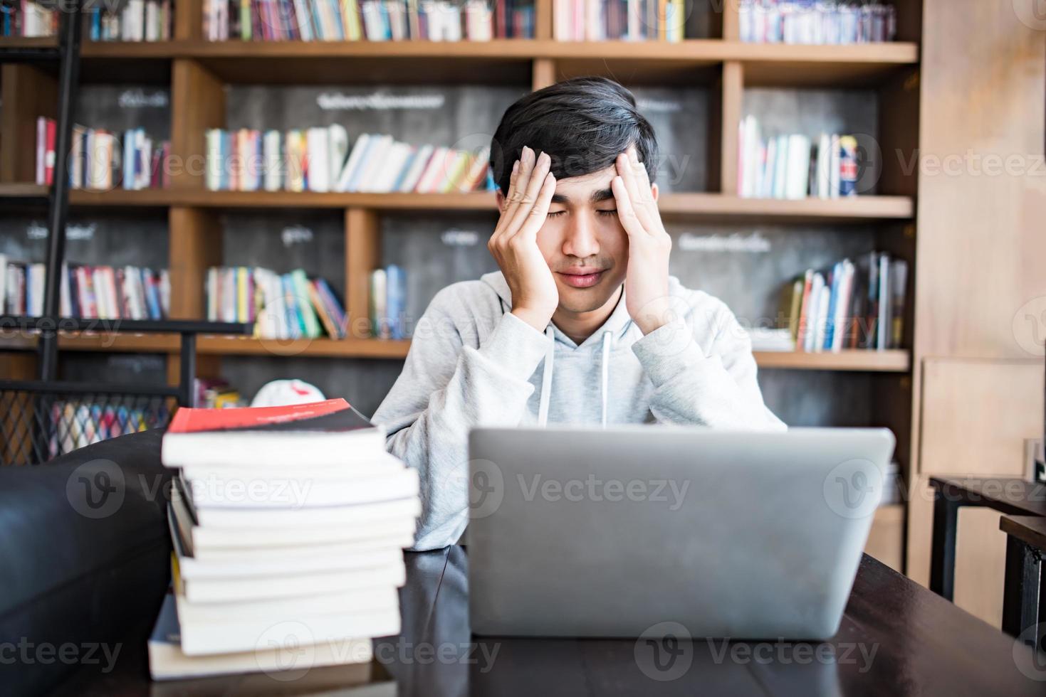 jovem estudante cansado de seu computador sentado em um café foto