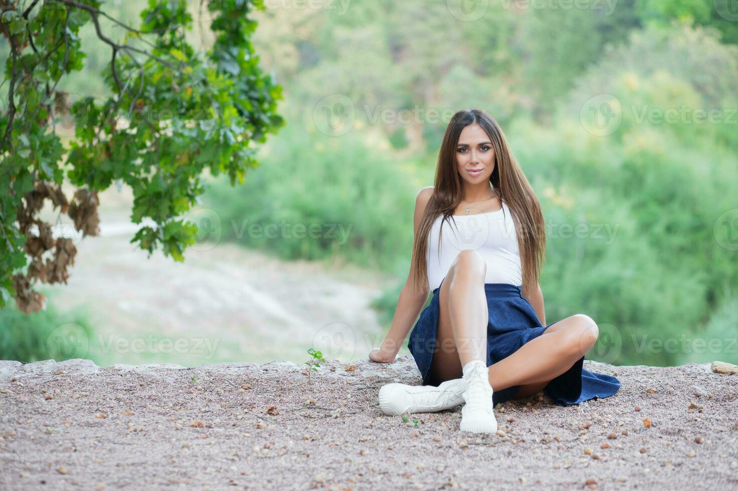 agradável morena posando sentado em uma trilha foto