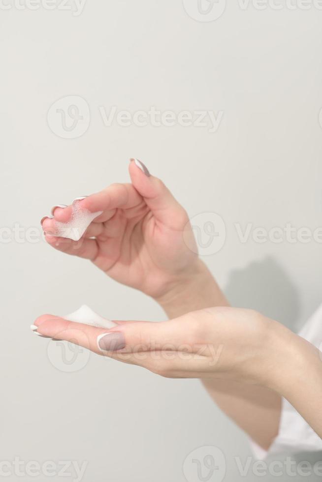 fêmea mãos com espuma mousse, pele Cuidado, hidratante, depois de bronzeado tratamento, mulher segurando espuma limpador para face pele. beleza Cuidado conceito. foto