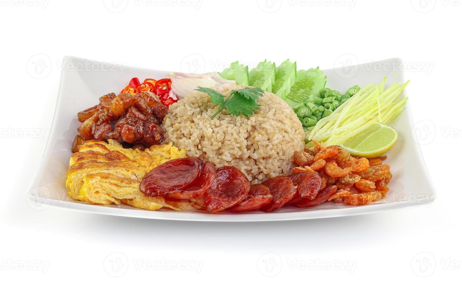 arroz temperado com pasta de camarão e cebola roxa, feijão, manga e ovo frito em prato branco com fundo branco foto