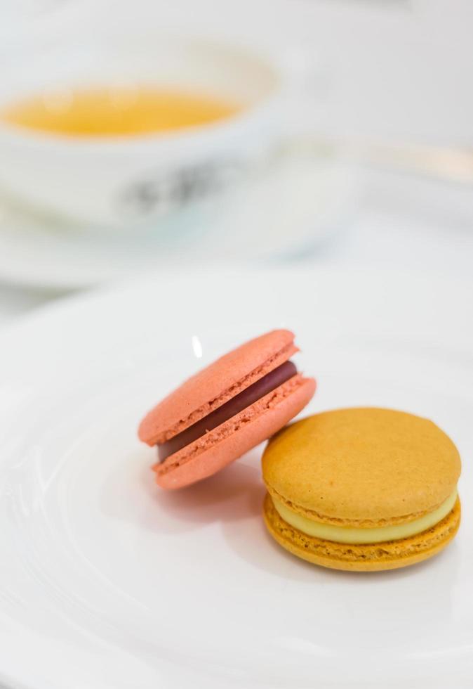 Macarons coloridos em um prato elegante branco sobre a mesa foto