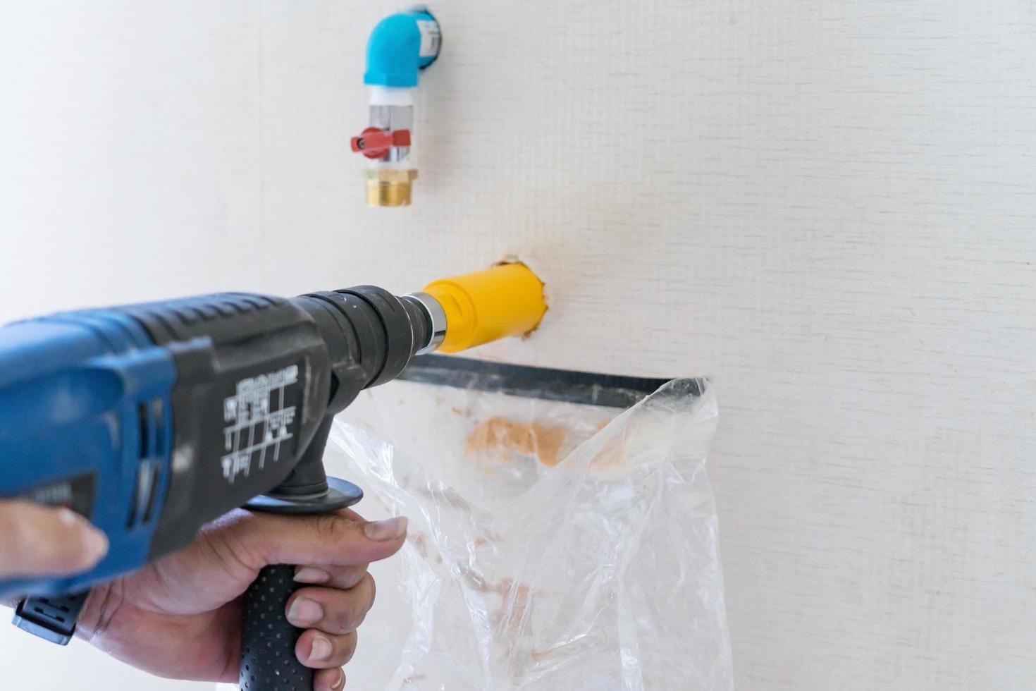 trabalhador usando uma ferramenta de perfuração em canteiro de obras foto