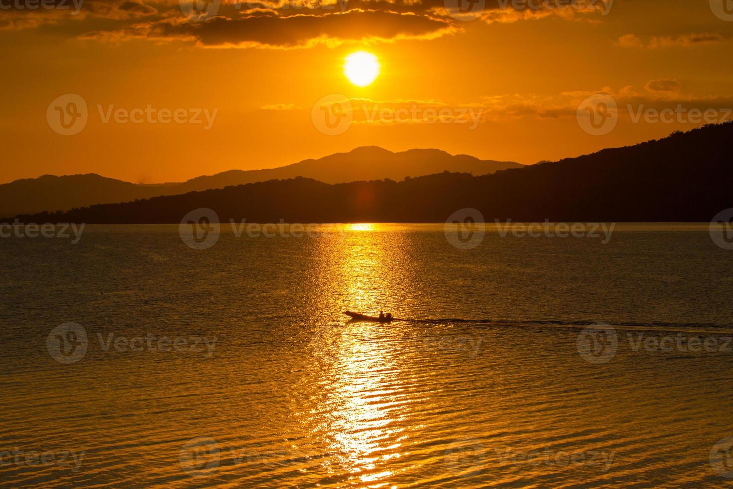 silhuetas de montanha e água ao pôr do sol foto