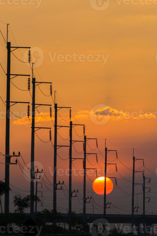 pôr do sol atrás de postes elétricos foto