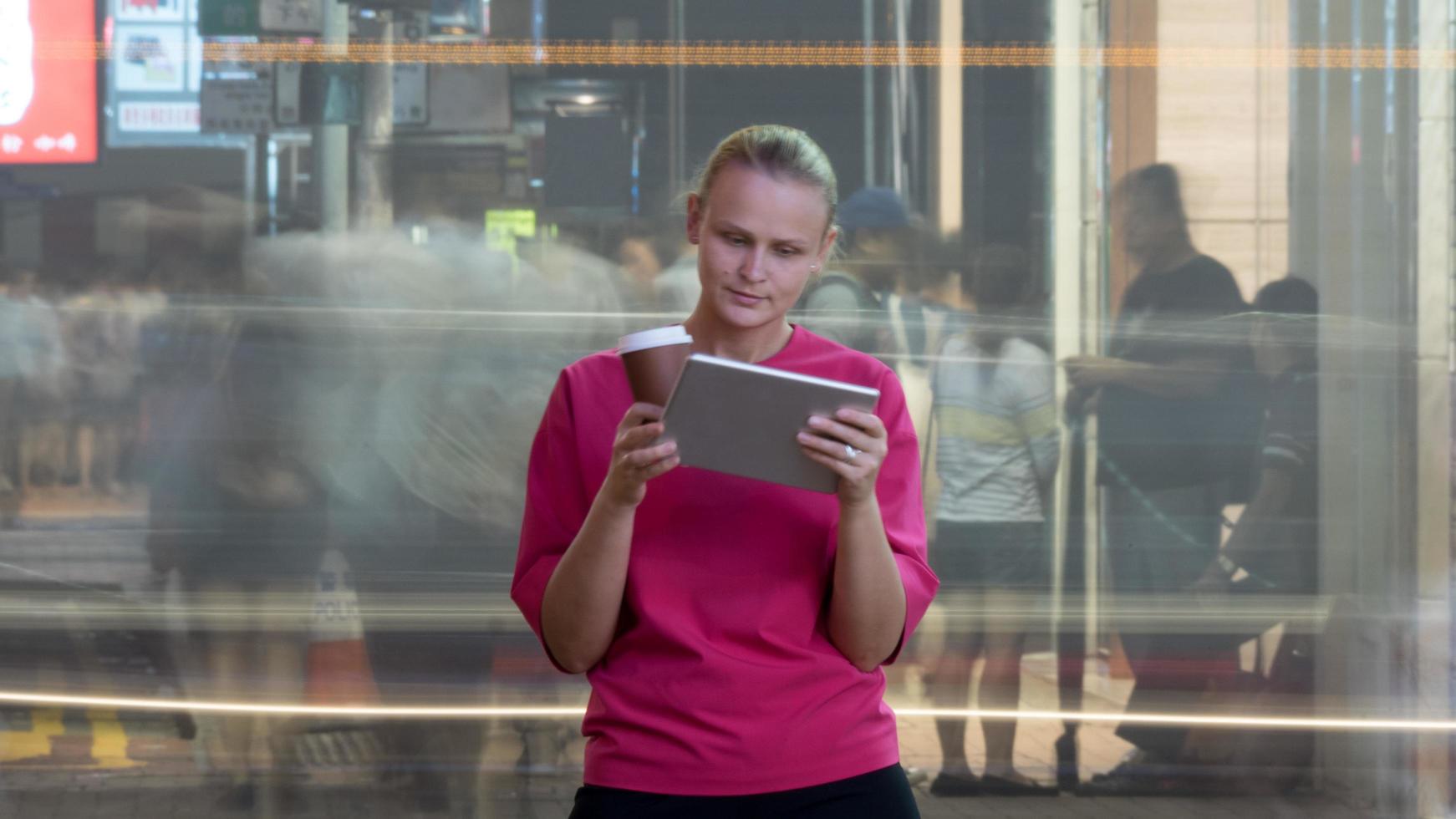 hong kong, 2020 - mulher com um tablet perto de uma rua movimentada foto