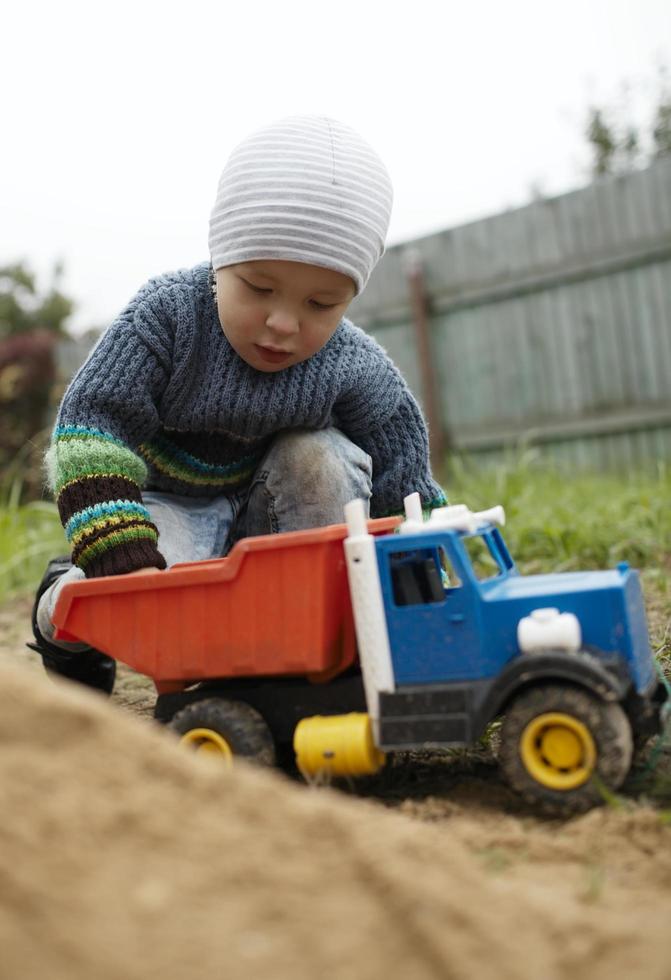 menino brincando com um caminhão de brinquedo lá fora foto