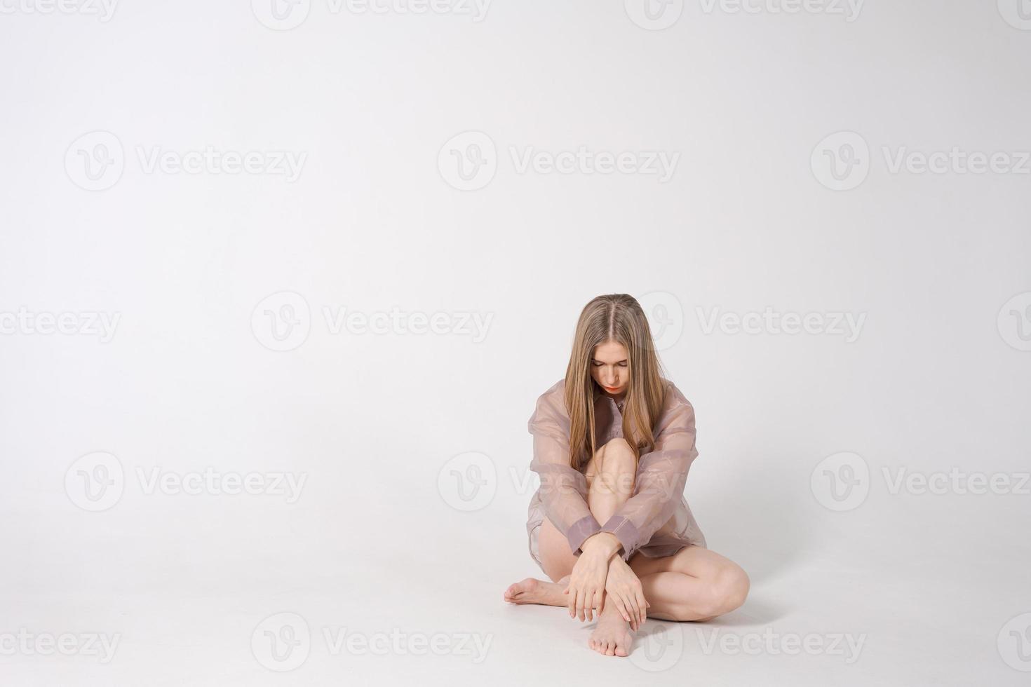 mulher é sentado em luz fundo dentro estúdio. ela é triste e depressivo foto