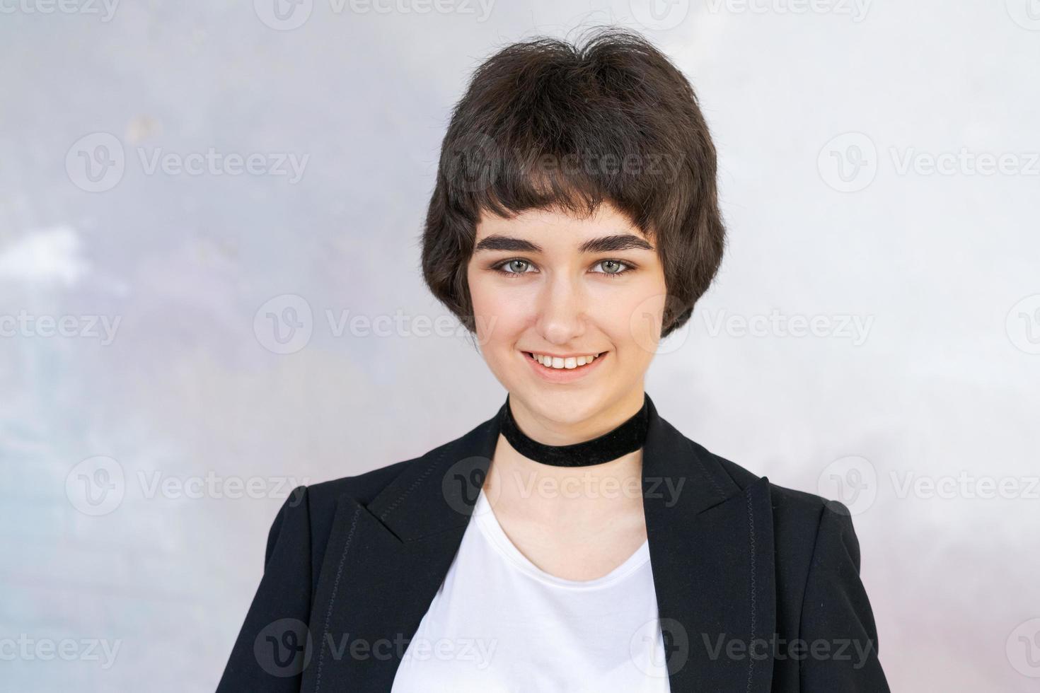 retrato menina dentro Preto Jaqueta com verificador por aí dela pescoço contra muro. bonita foto