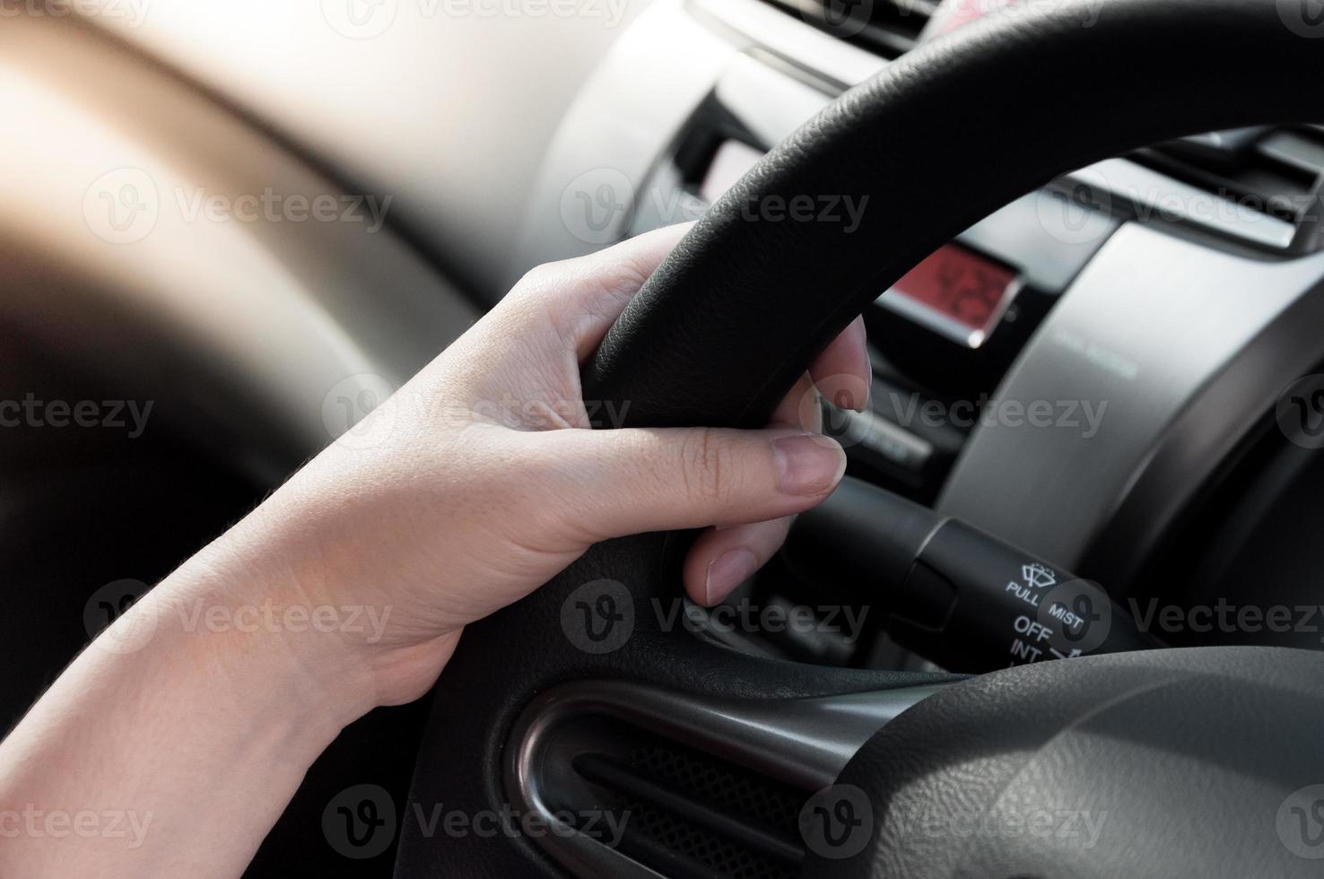 mulher mão segurando em Preto direção roda, mulher dirigir uma carro foto