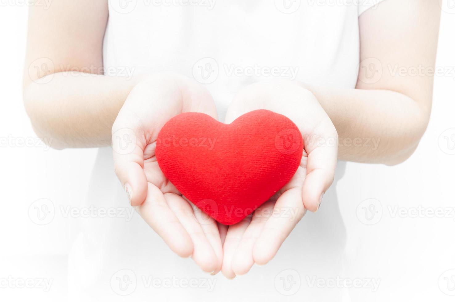mulher segurando e protegendo dar uma vermelho coração forma em branco fundo close-up, símbolo do amor ou namoro dia dos namorados dia foto